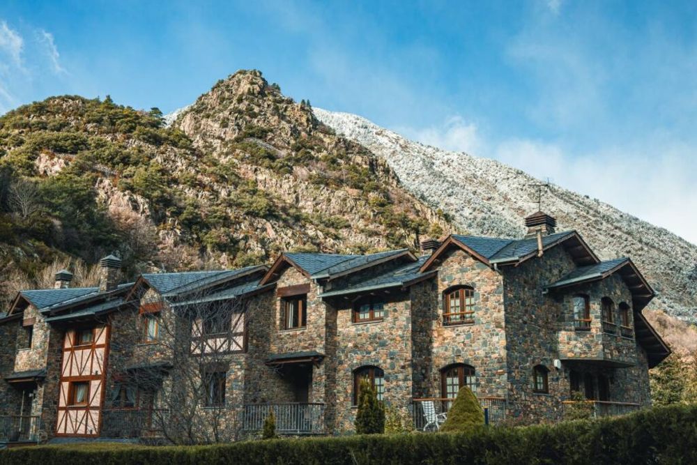 Edificio de piedra típico de Andorra con la montaña detrás, cómo es vivir en Andorra